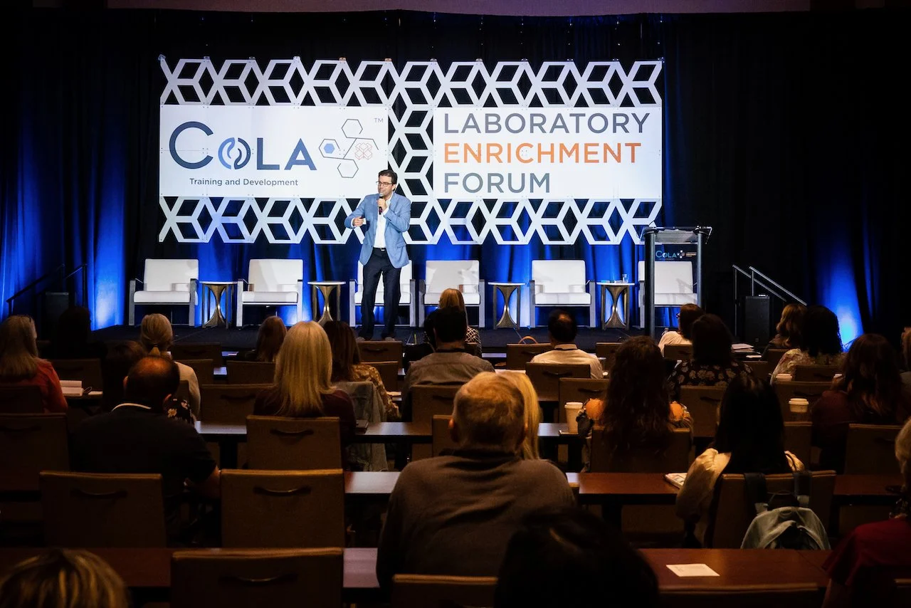 20230504 Healthy Humorist Doctor Brad Nieder On Stage Long Shot with COLA Laboratory Enrichment Forum Signs.jpeg