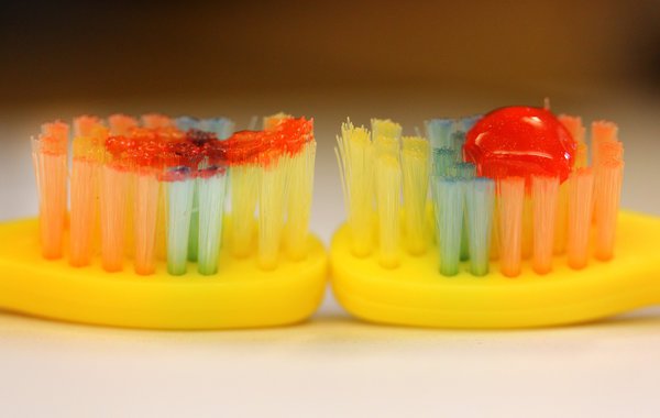 How to use fluoride toothpaste for kids: a smear on the left (good) vs a pea sized amount on the right(bad)