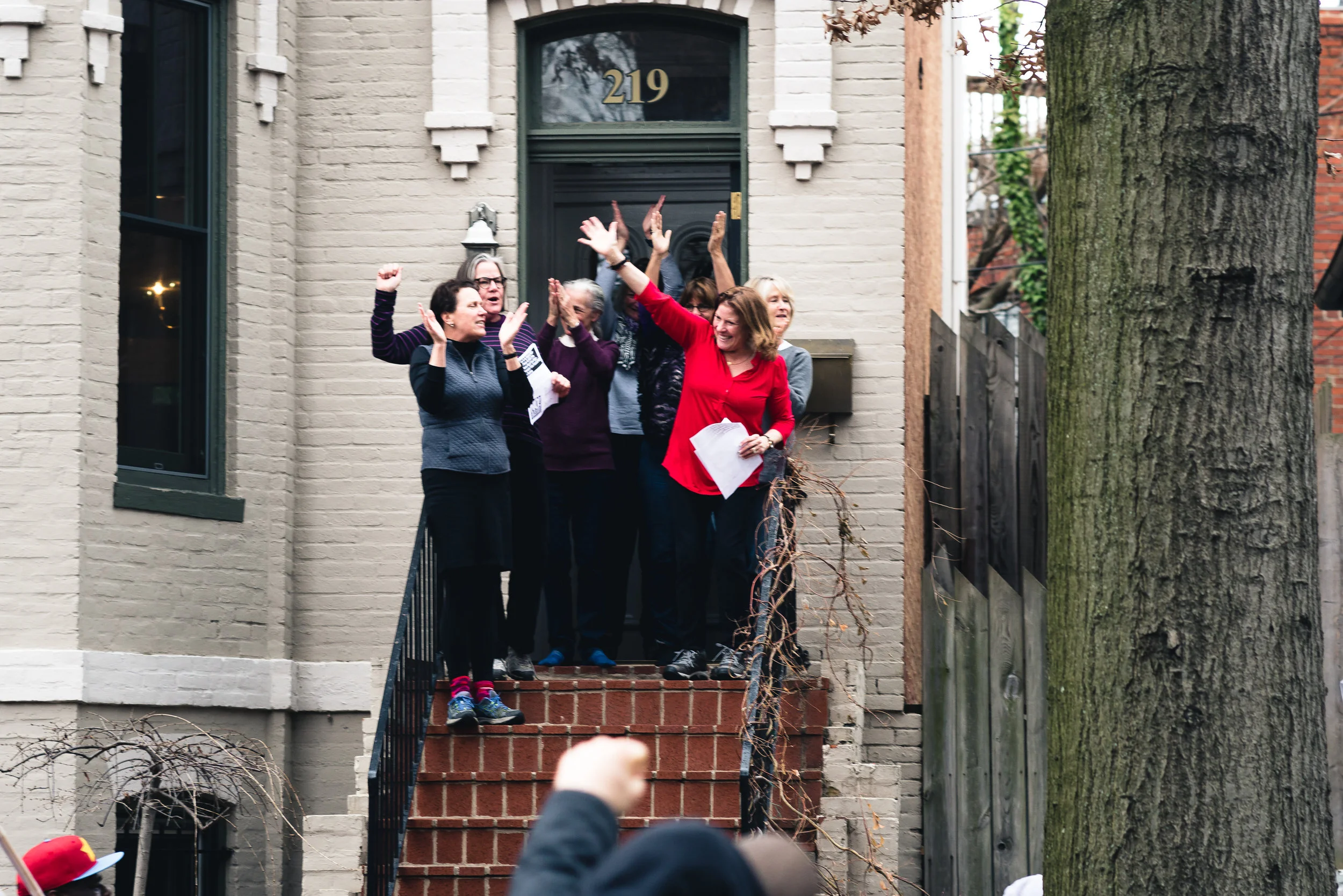 Women come out on their stoop to greet and cheer on protestors marching down 3rd St NE, in the Capitol Hill neighborhood.