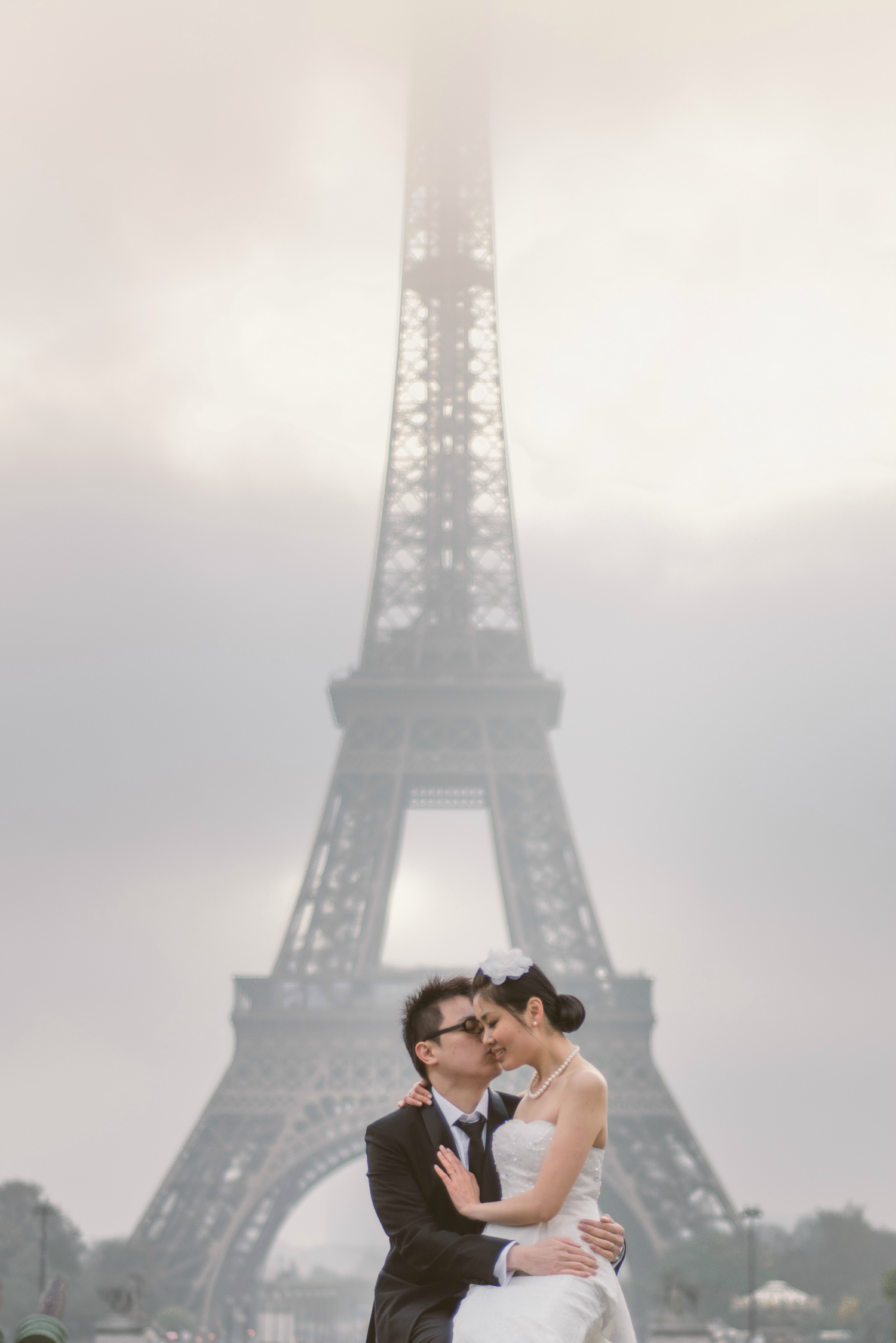 Prewedding session in Paris couple kissing in front of the foggy Eiffel Tower