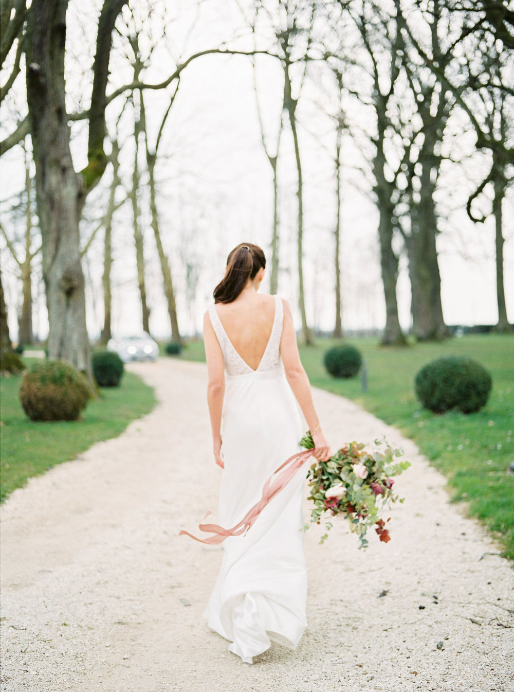 Bride with wedding bouquet and silk ribbons floating in the wind