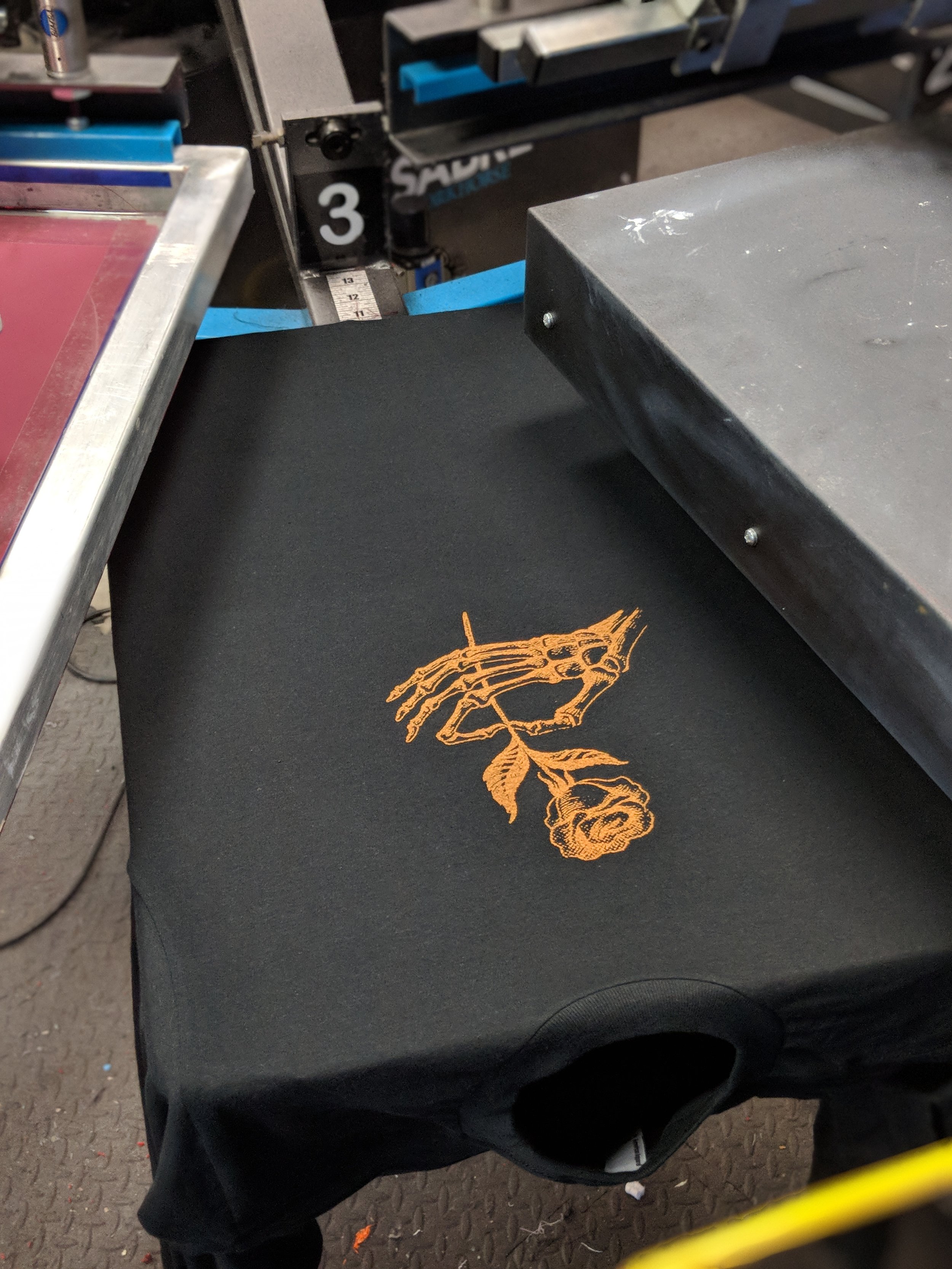 Specialty ink custom screen printing of a skeleton rose graphic for a Texas streetwear brand.