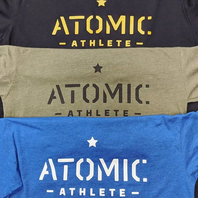 Stack of custom moisture-wicking gym shirts screen printed for our long-term client Atomic Athlete in Austin.