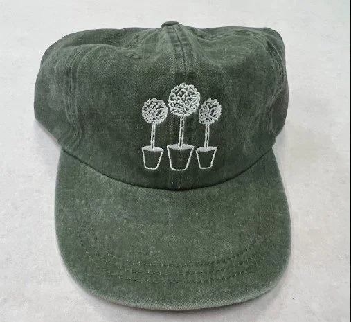 Custom embroidered corporate swag hats on green corduroy produced for a Texas business.