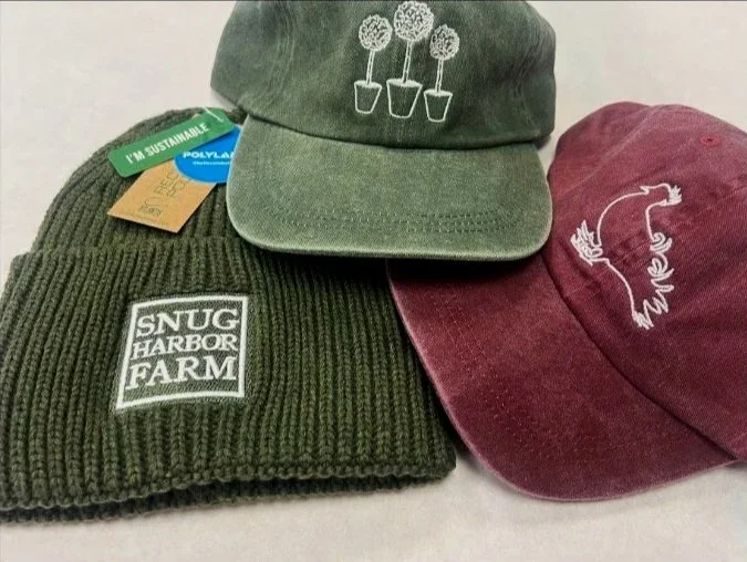 Custom logo embroidery on winter beanies produced for Snug Harbor Farm.