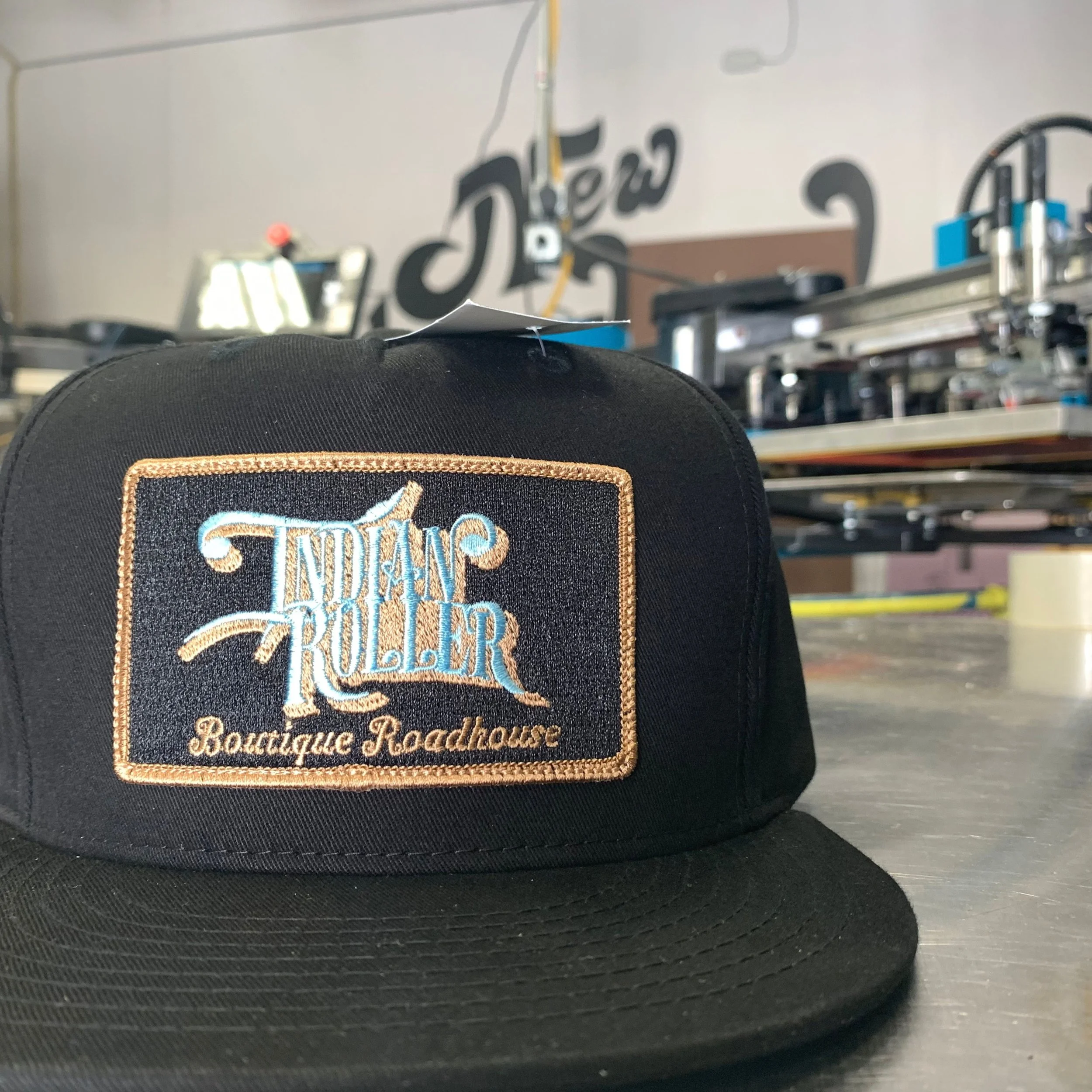 Custom embroidered black trucker hat featuring a detailed white business logo.