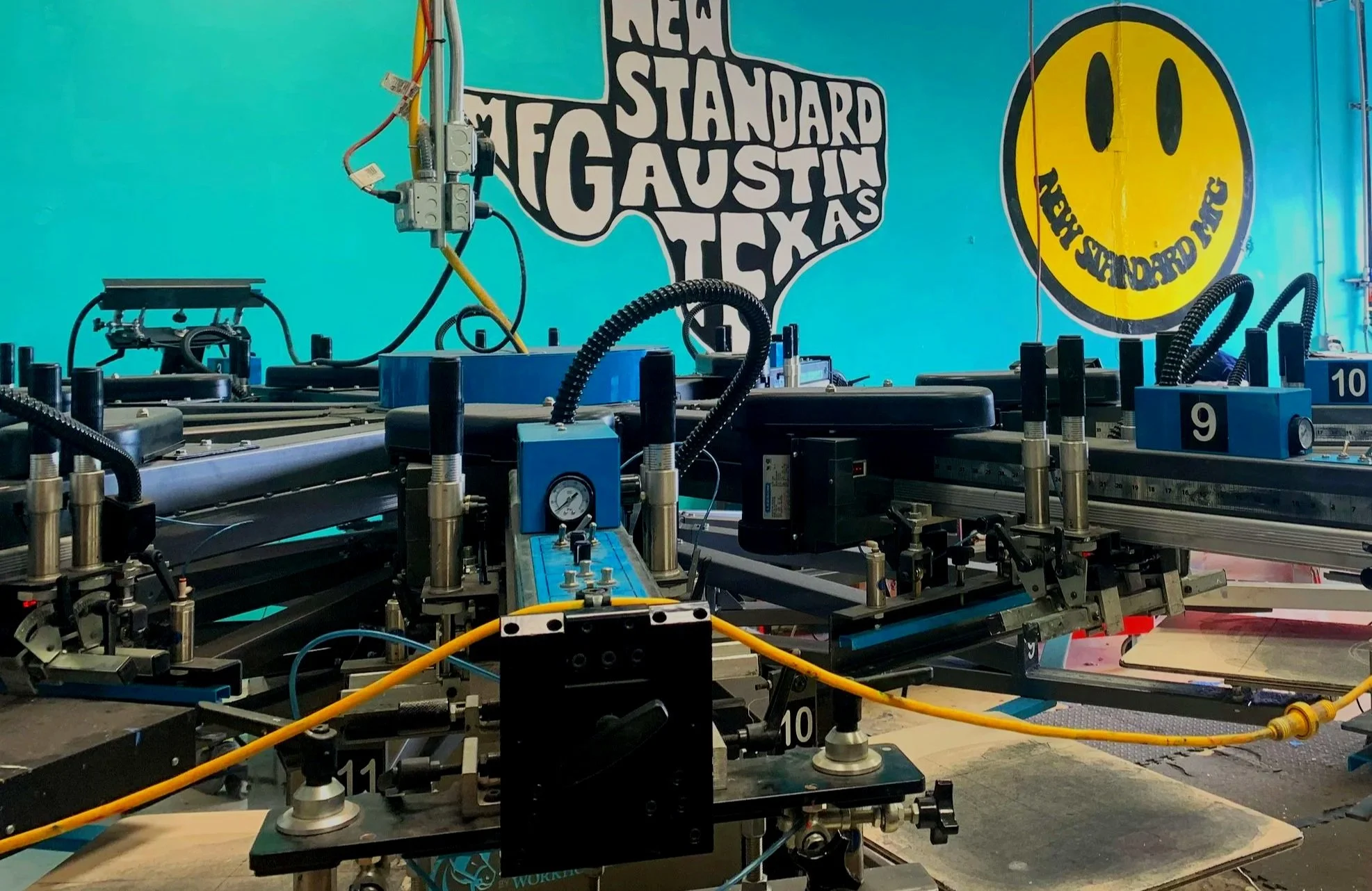 Automatic screen printing press printing custom t-shirts at New Standard Mfg in Austin Texas