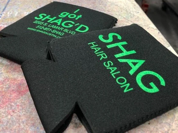 Custom screen printed black koozies made for local Austin business Shag Hair Salon.