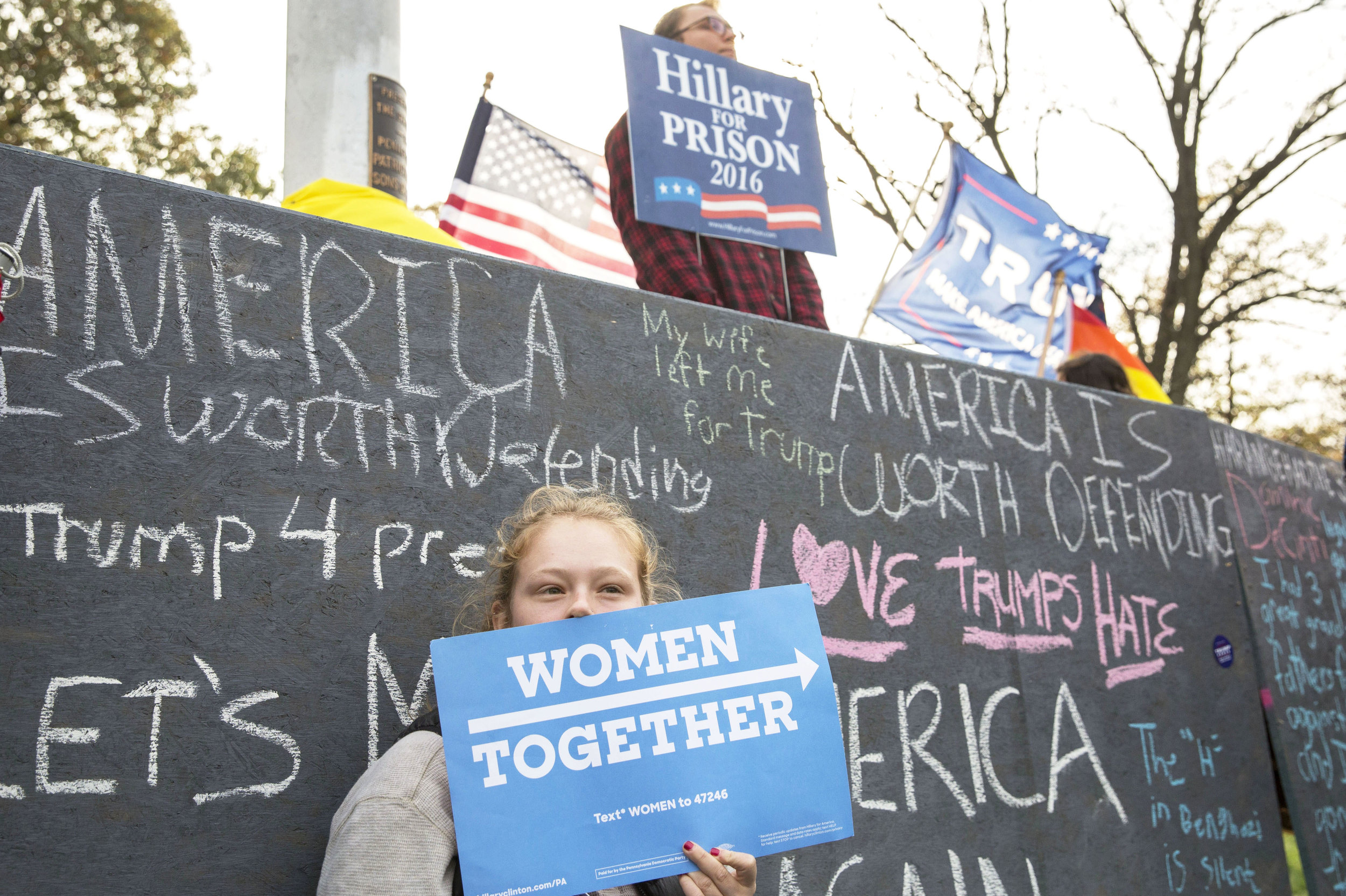 Tessa Sontheimer (junior-community environment and development) holds a sign in support of Hillary Clinton in front of a wall that was built by the Bull-Moose party on Old Main on Tuesday, Nov. 1, 2016.