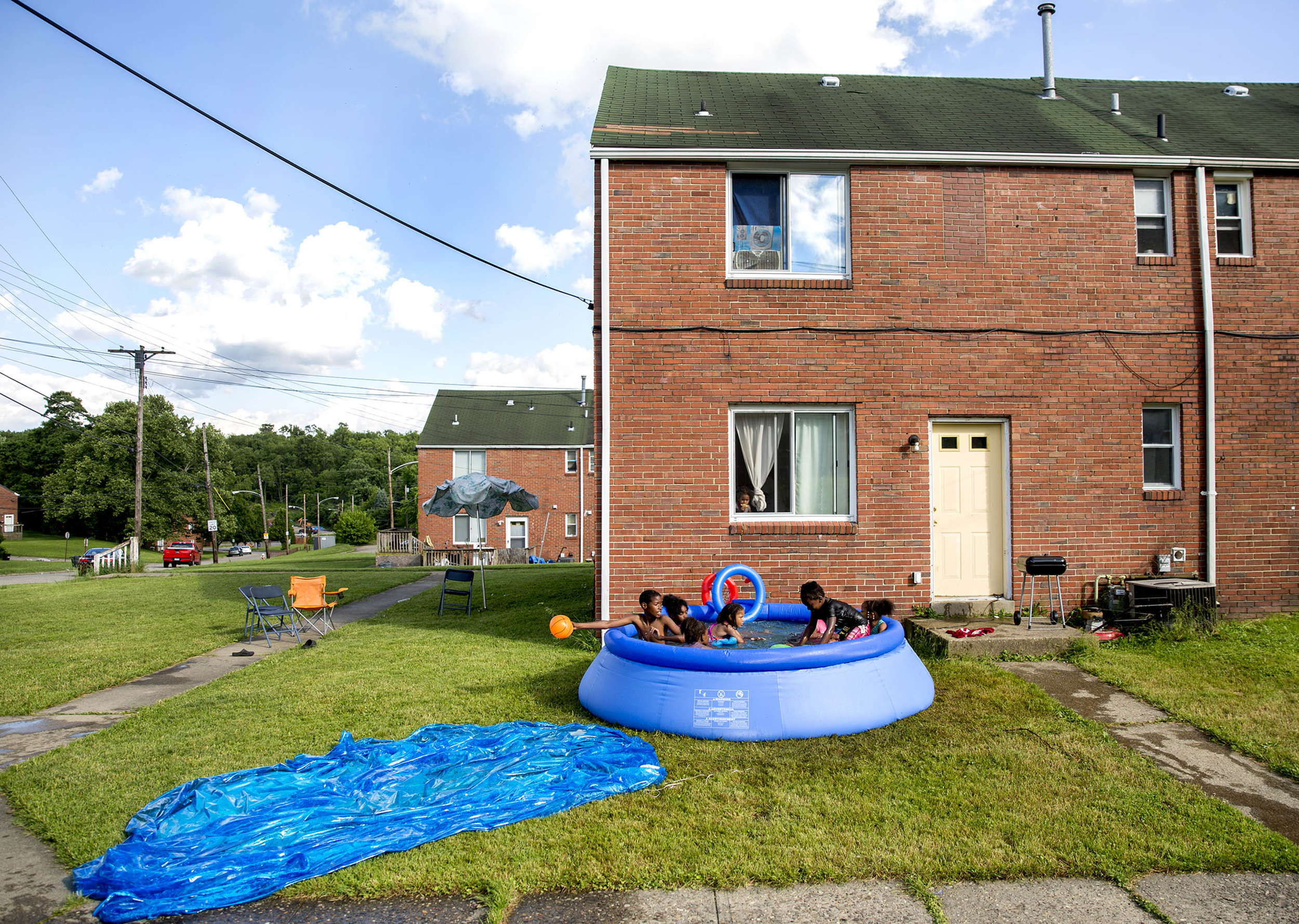  Jemarcus Compton, 12, of Clairton, stretches his arm out to keep posession of the ball while playing with friends in an inflatable pool on Monday, June 4, 2018 at the Century Townhomes in Clairton. Several hundred residents of the Century Townhomes 