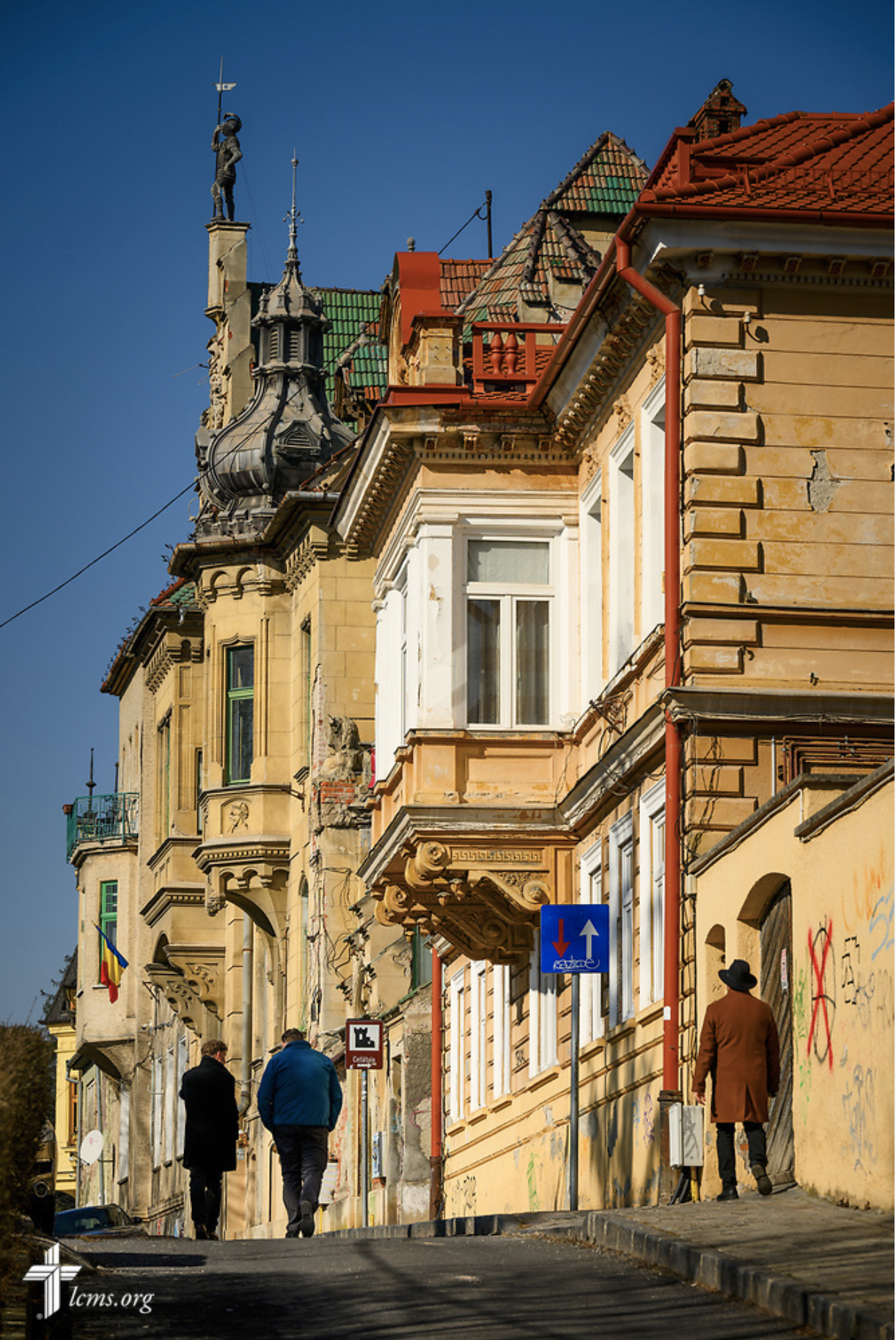  The Rev. Sorin Horia Trifa (right, with hat), LCMS alliance missionary and pastor in the Confessional Lutheran Church in Romania (Biserica Lutherană Confesională din România), walks to the St. Mary's Lutheran Center (seen with the statue of the armo
