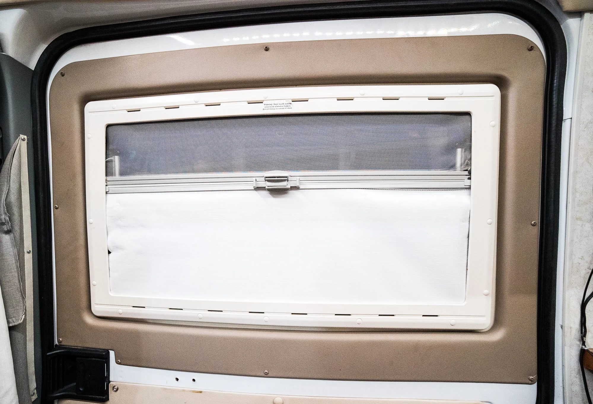The windows are really pretty slick. They're made of double-paned plexiglass for insulation and they hinge outward from the top, so you can have them open even in light rain and not soak your interior. Pull the shades down and you've got bug-screens. Pull them up and you've got full blackout shades.