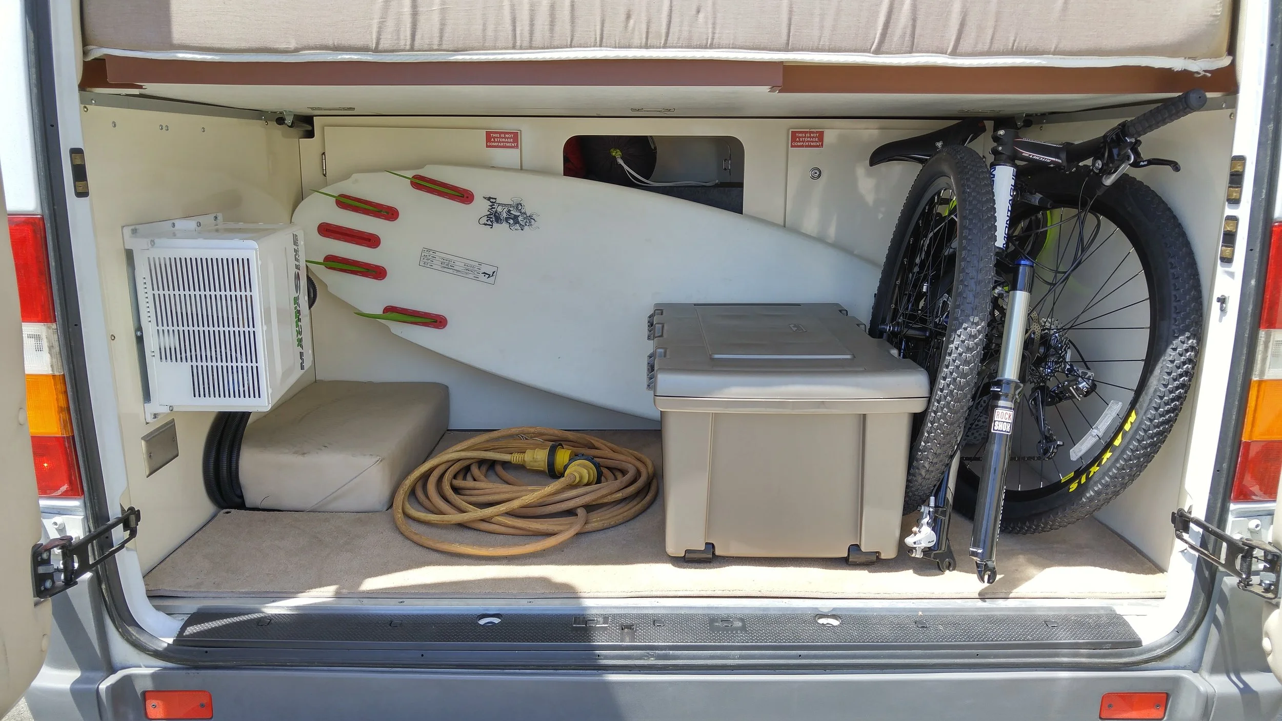 The trunk (under the bed) hasn't been this empty since I bought the thing, but I'm using this shot to show how neatly the Montague folding mountain bike and the 5' 8" surfboard fit in there. There's now also a snowboard, a guitar, backpacking gear, a drone, and all kinds of other stuff. You can also see the 3000 watt hybrid inverter bolted to the left side. Hidden in there is also 200aH of lithium battery, both installed by AM Solar in Springfield, OR.