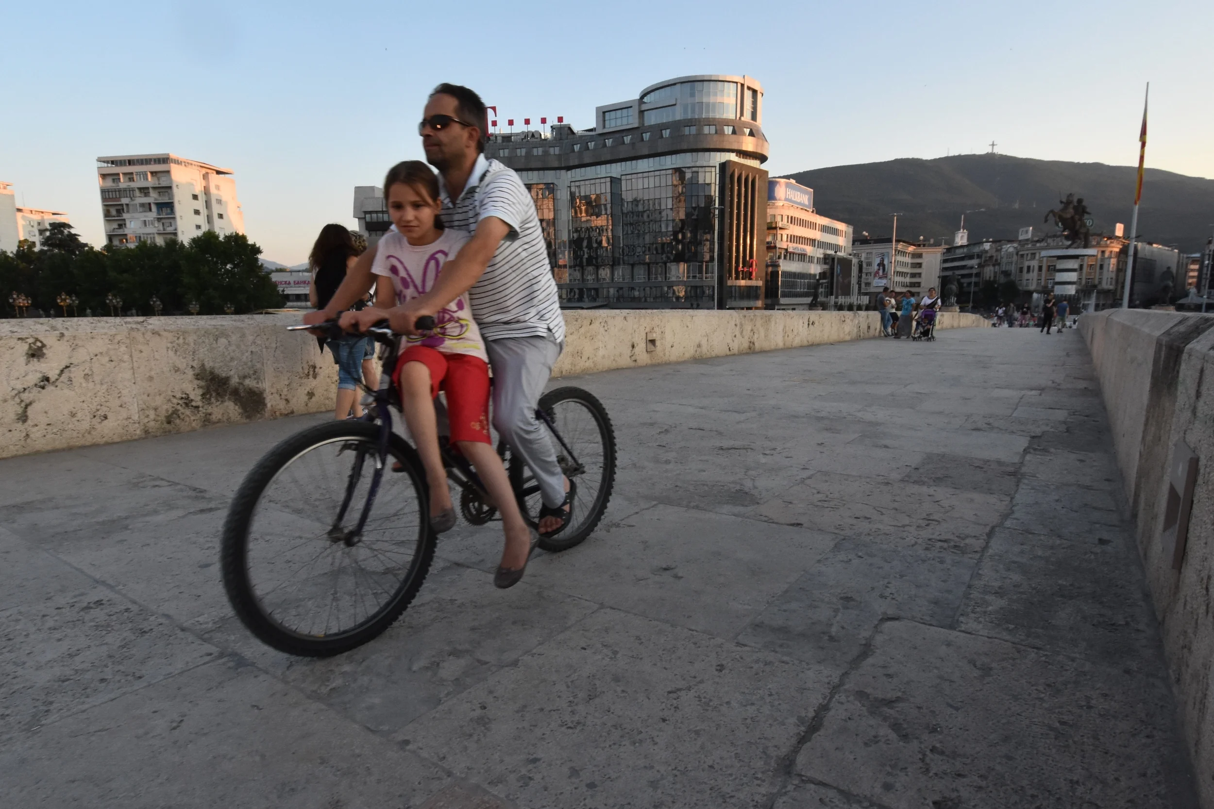 Father and daughter ride their bike across a bridge in Skopje, Macedonia