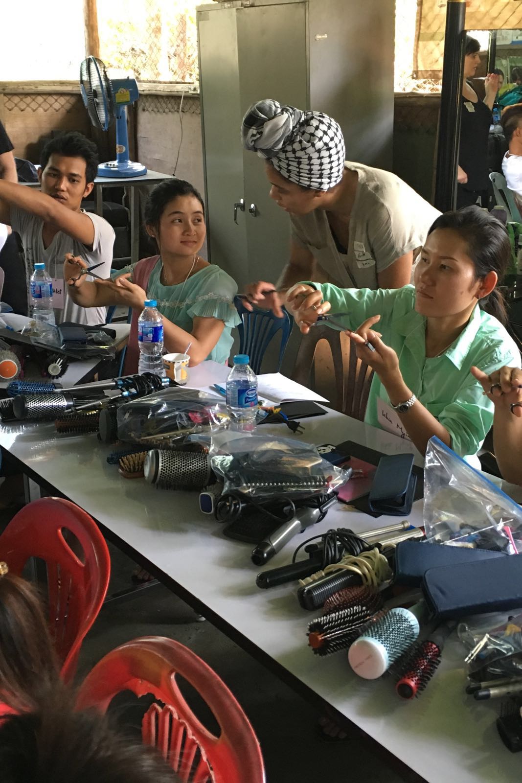 HAUS Color Director Nikki Brown (center) teaches Hser Kaw Wah how to hold her shears properly.