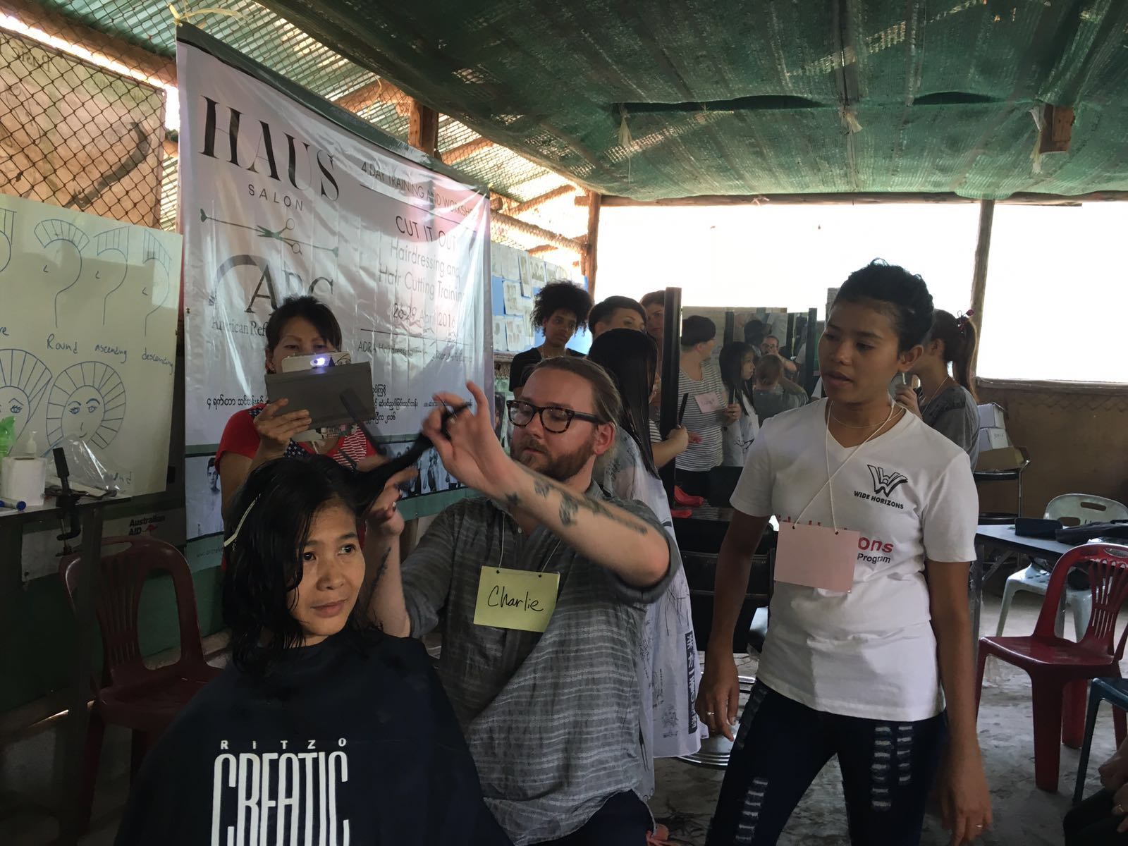 Students watch while Charlie demonstrates a new style for Thi Dar Aung.