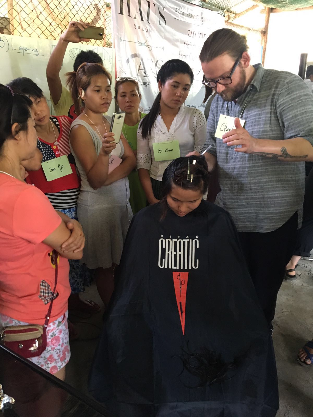Charlie working on Phadkaew's style as stylist students observe
