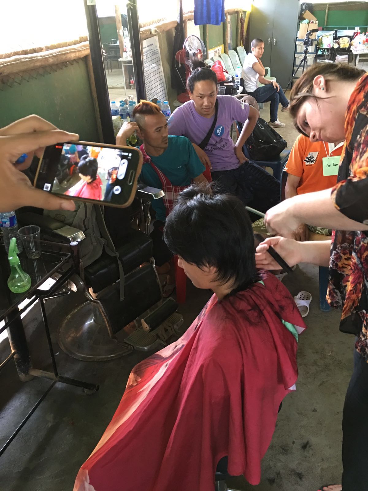 Natalie from HAUS South Minneapolis creates a modern men's haircut as a student documents the process on a smart phone.