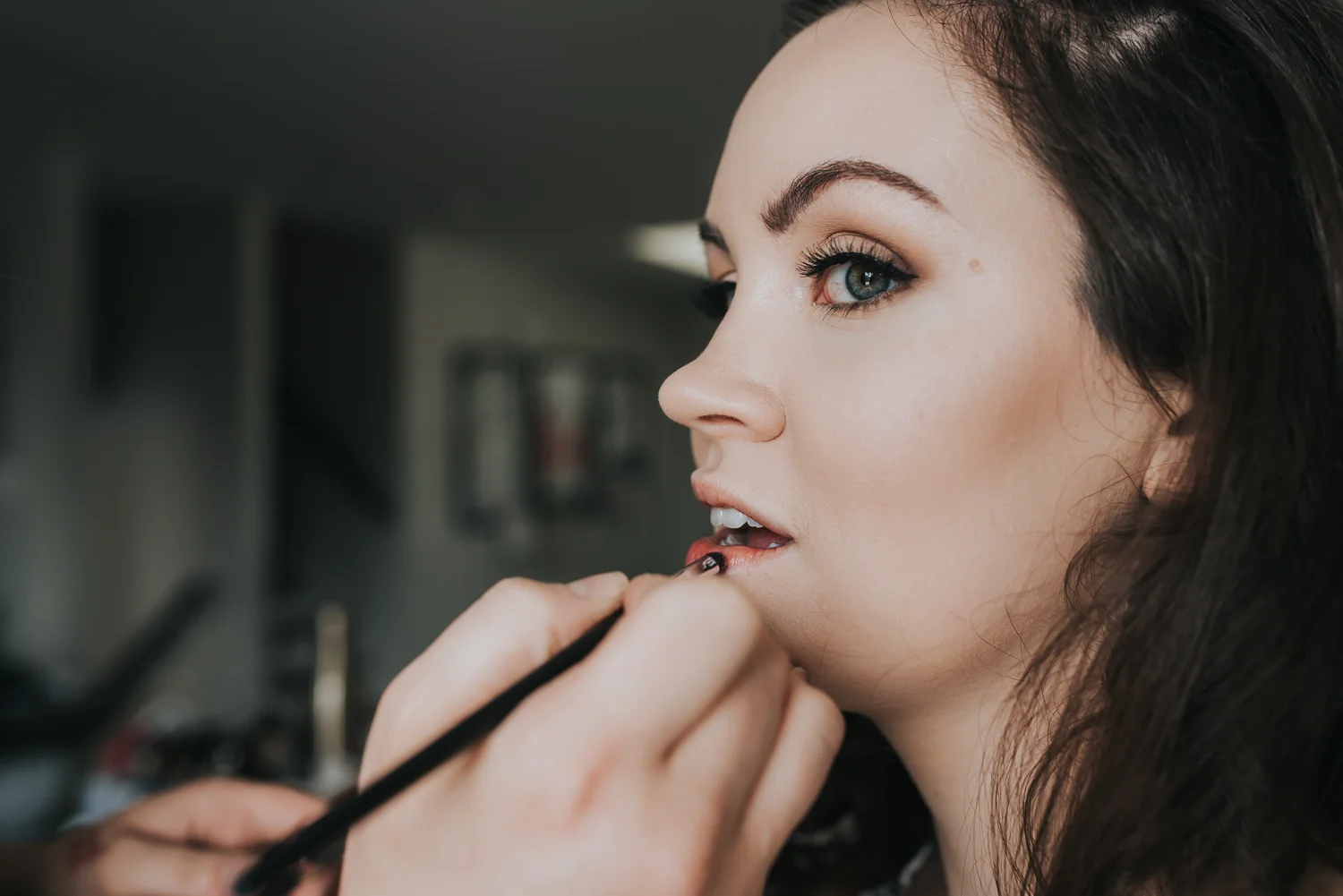 Bridal preparation makeup artist applying rose lip stain