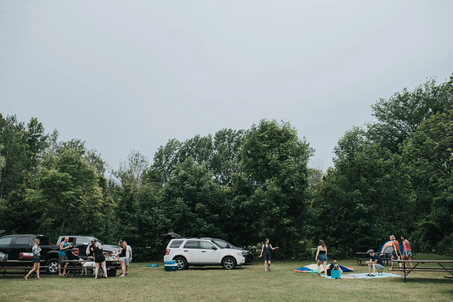 Family camp set up and preparations picnic tables and cars with family members and friends