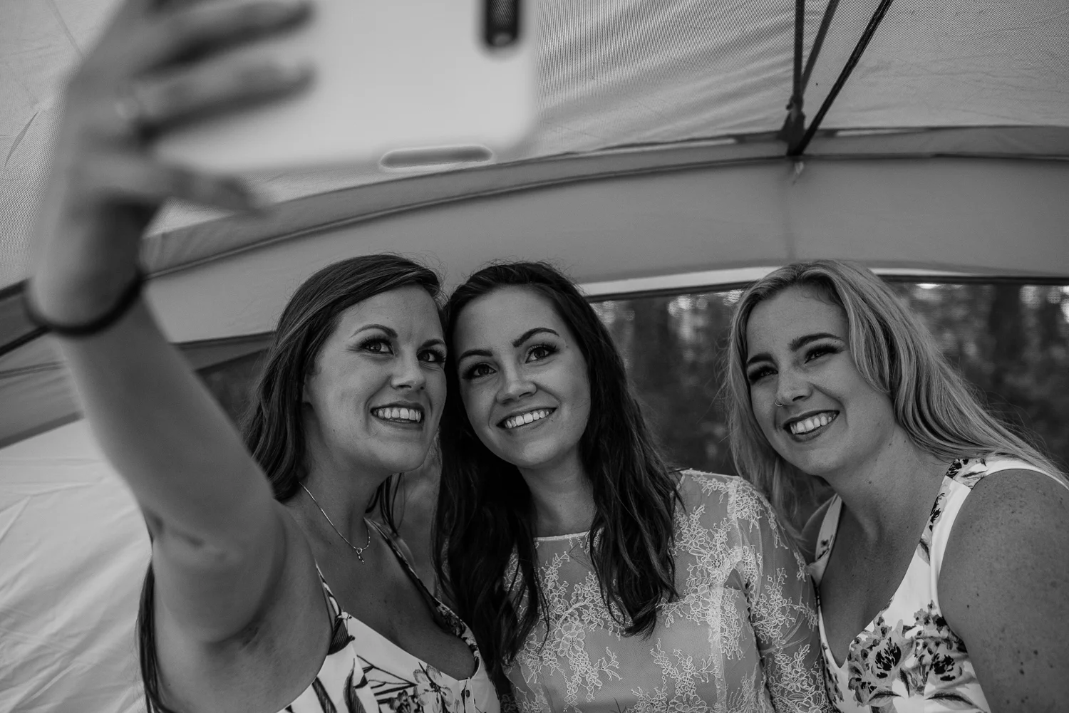 Bride and bridesmaids taking a selfie after getting into their dresses