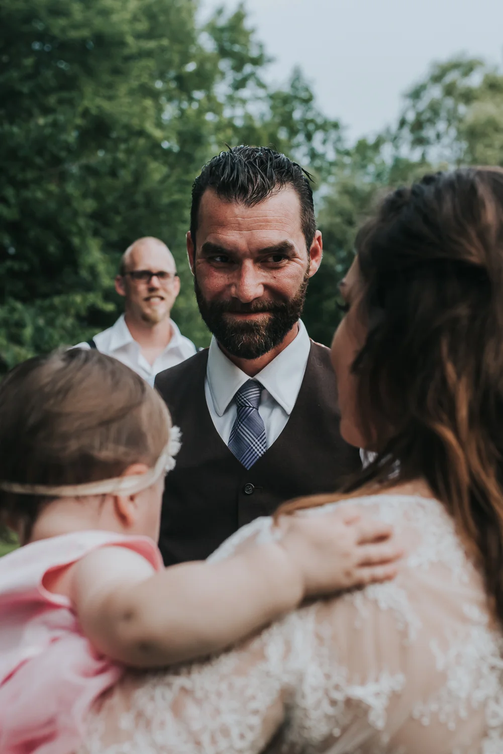 Groom looking at his soon to be wife and his daughter dressed in blush and pink