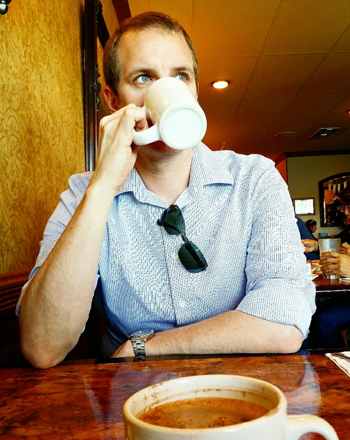 man, his green eyes, and his coffee