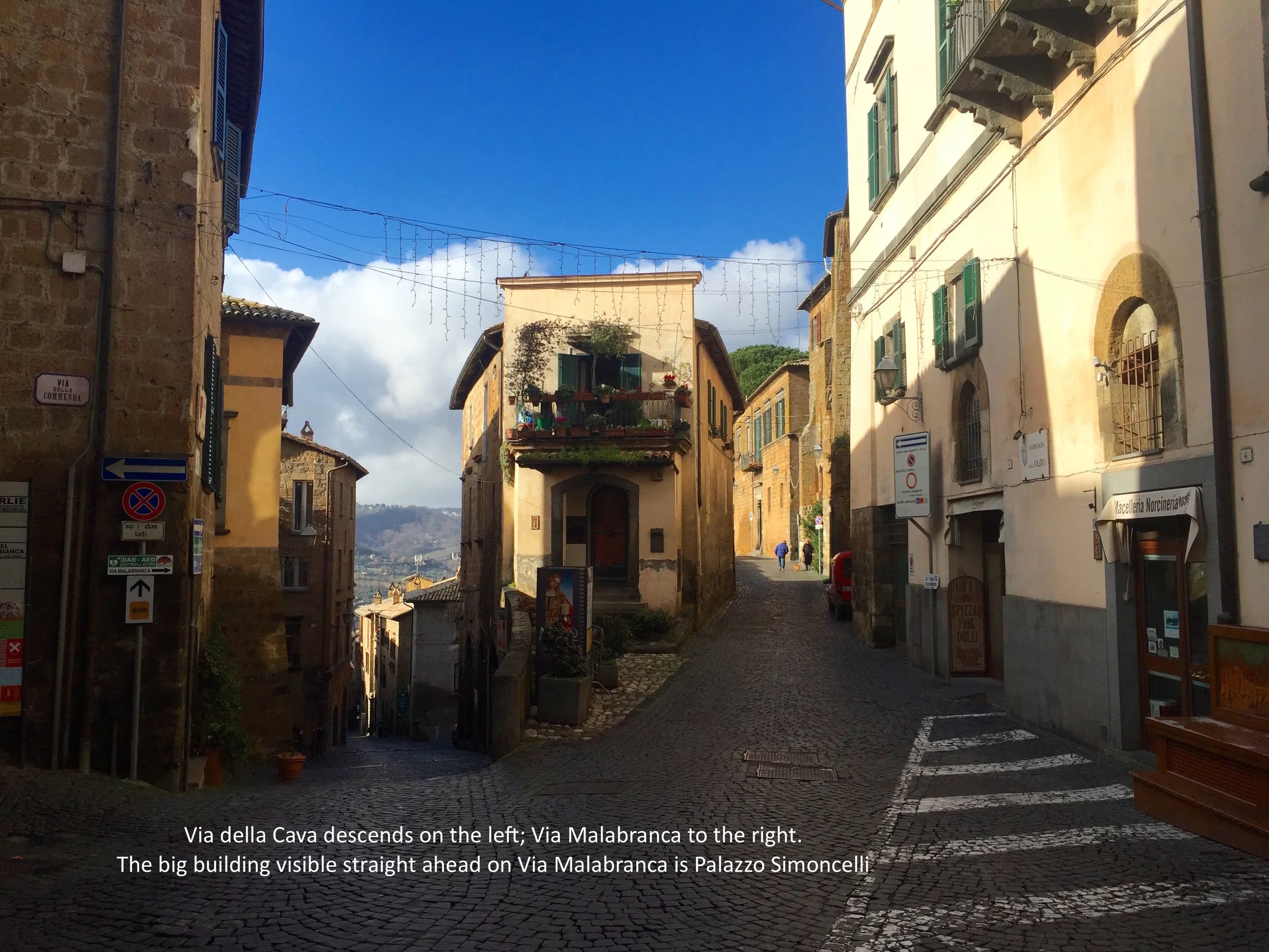 Via della Cava descends on the left to the Porta Maggiore. Via Malabranca is the right fork of the Y. Palazzo Simoncelli is the sun-lit building straight ahead on Via Malabranca.