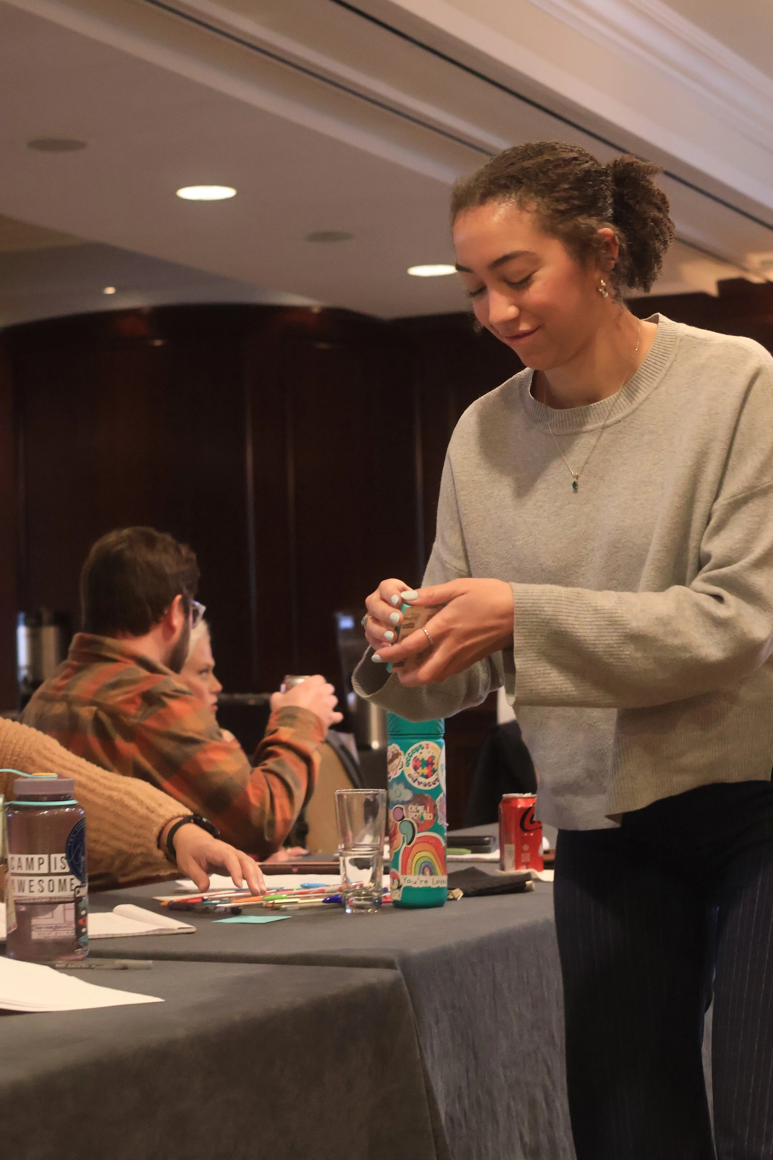 A young woman is smiling and looking down at a stack of post-it notes and she pulls one from the stack.