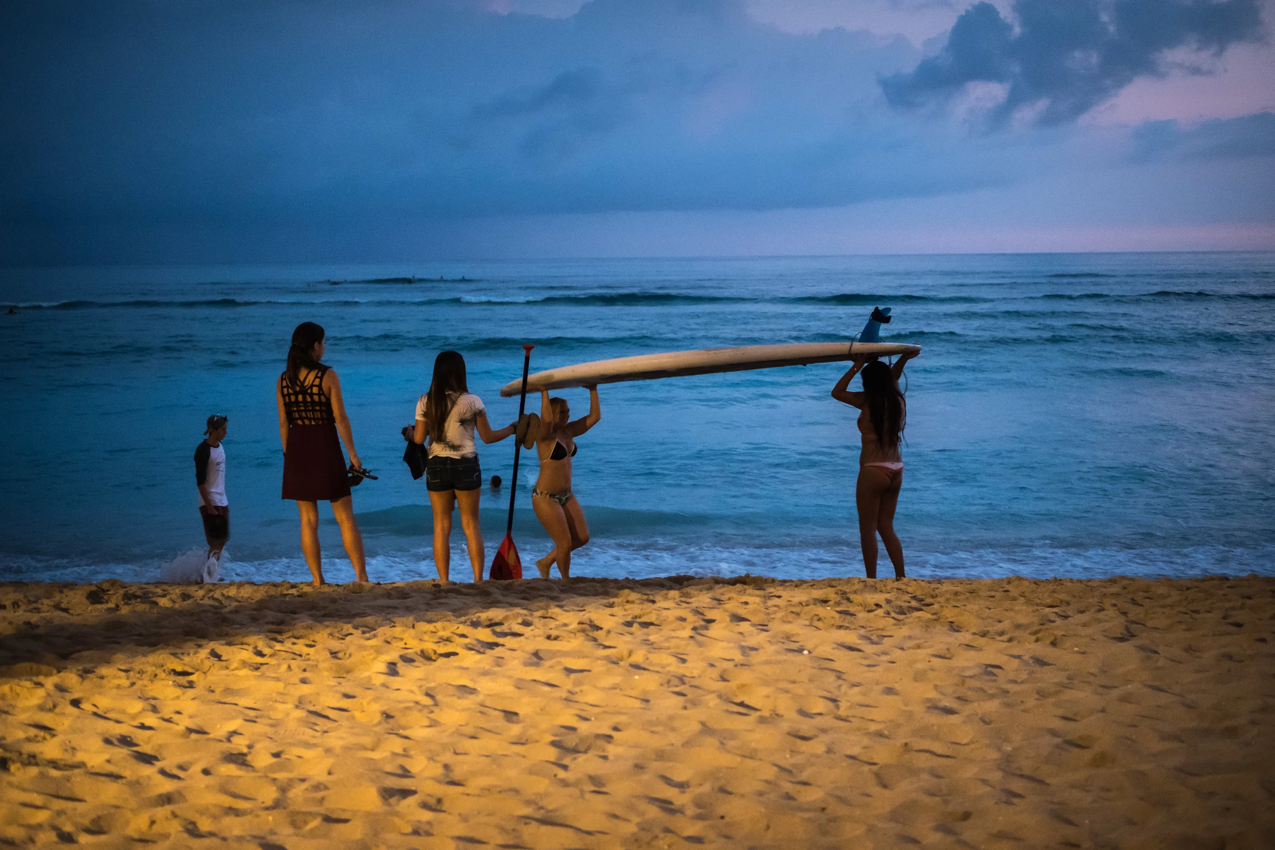 As the sun dipped below the horizon, it didn't take long for it to get dark. I was photographing surfers and paddle boarders coming ashore when I noticed a hotel's flood light illuminating a patch of sand, so I positioned myself hoping that some action would take place in or near the light. I like the warm yellow light contrasting with the blue ocean and sky and that last hint of pink. I think that just enough light reaches the subjects and ensures that they weren't in silhouette. 1/35 @ f2.0, ISO 3200. 