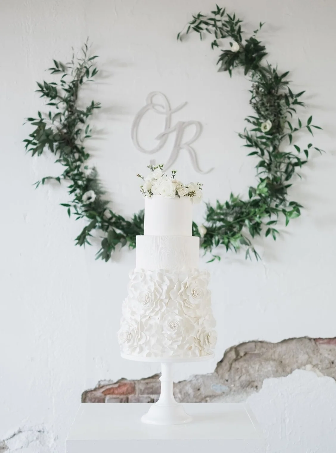 White wedding cake with cascading sugar flowers and wood grain