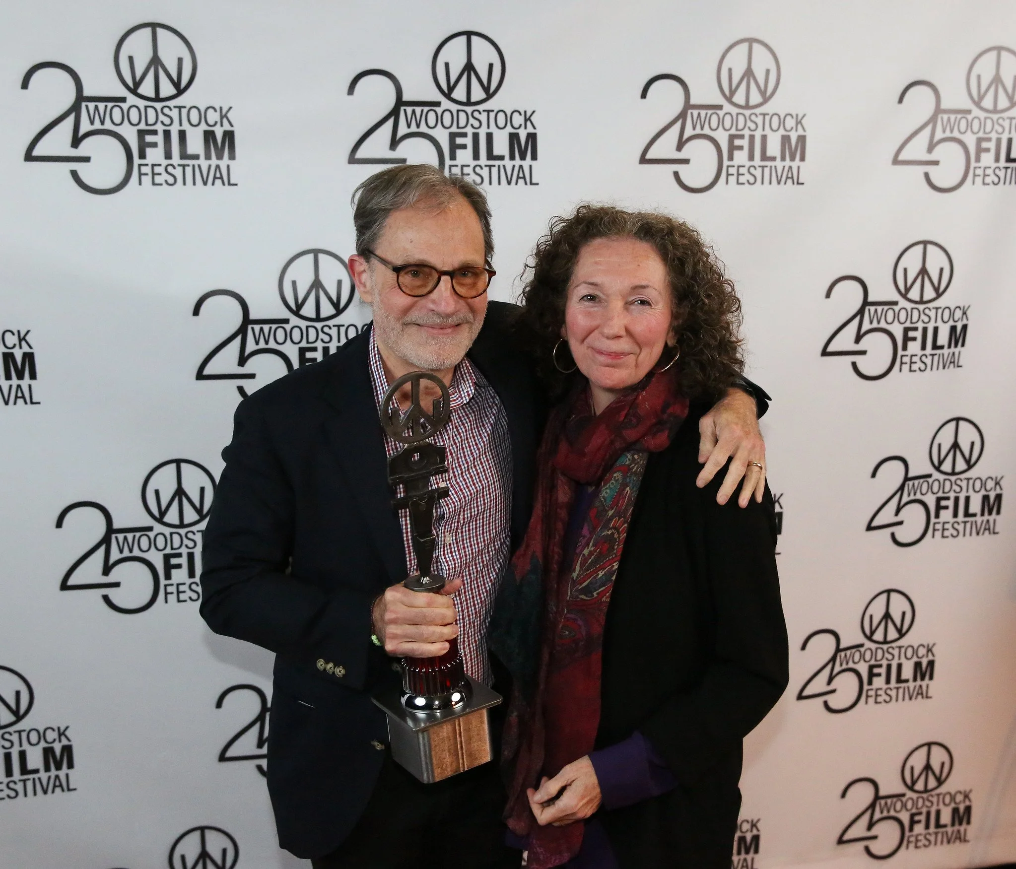 A man and woman smiling and posing with a film award at the Woodstock Film Festival.
