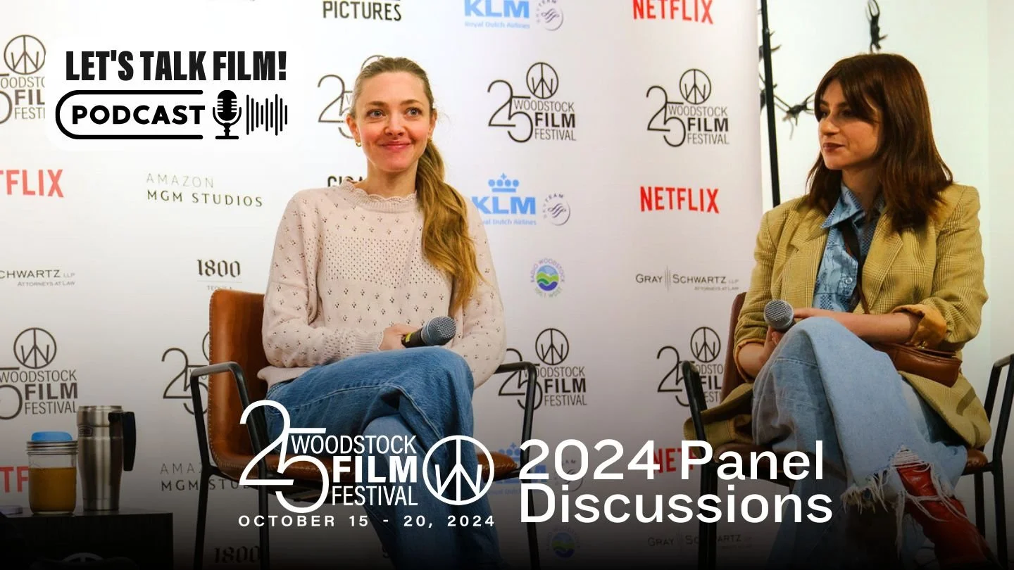 Two women sitting on chairs at a Woodstock Film Festival panel discussion, each holding a microphone, with a backdrop displaying festival and sponsor logos. The event is part of the 25th Woodstock Film Festival from October 15-20, 2024.