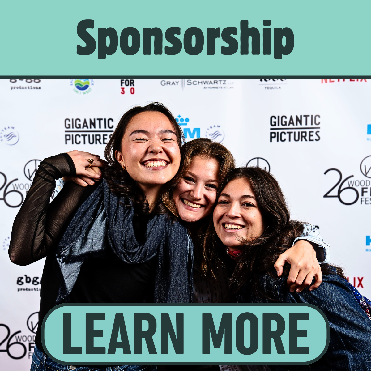 A group of three young women smiling and hugging at an event with a backdrop that reads 'Gigantic Pictures' and '26th Woody Film Festival'.