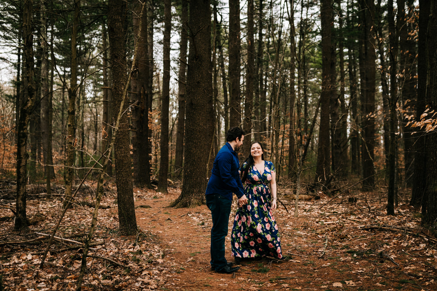 Fun couple dancing in the forest wearing blue floral dress