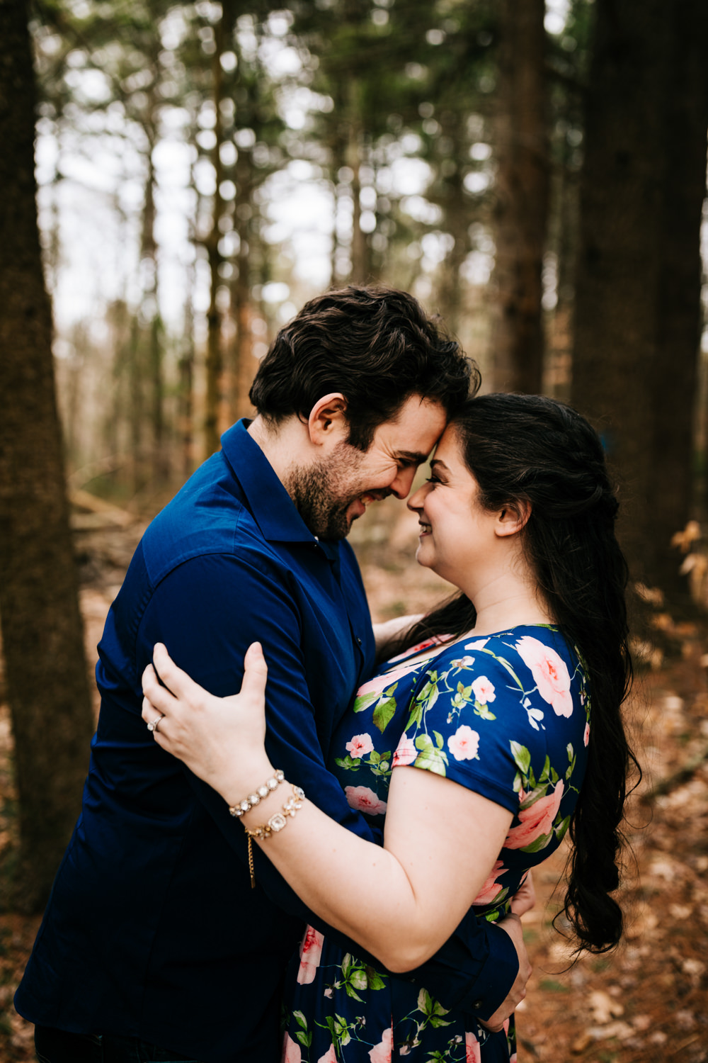 Couple smiling and kissing with woman wearing crystal bracelets in woods near Albuquerque