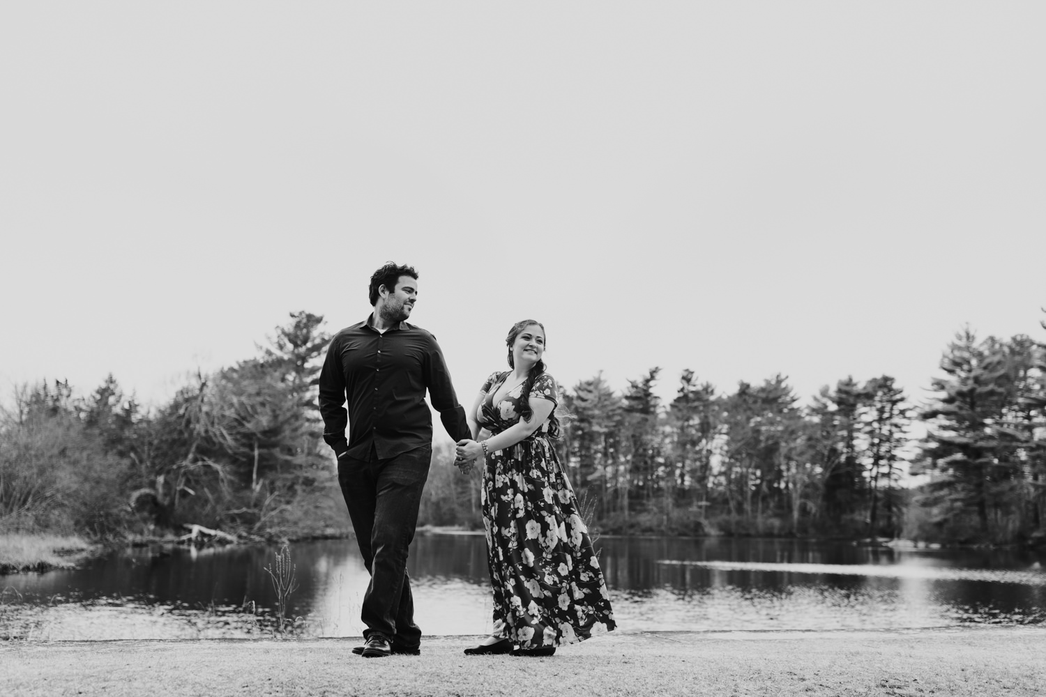 Black and white of couple walking on trail on waterfront in Massachusetts