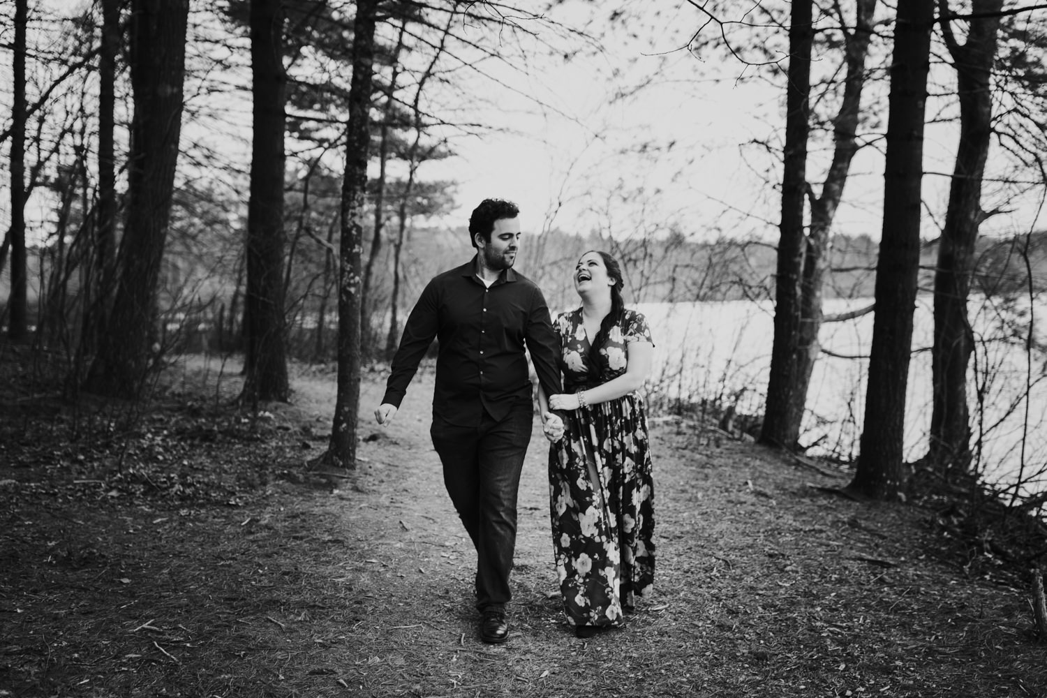 Couple walking and laughing on trail in woods near lake in New England