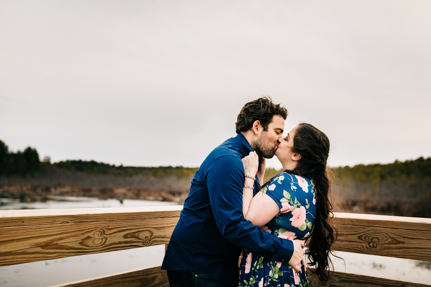 Couple kissing on dock of a lake in Massachusetts