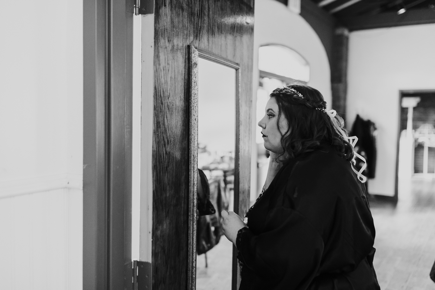 Bride looking at herself in mirror before wedding ceremony in black and white