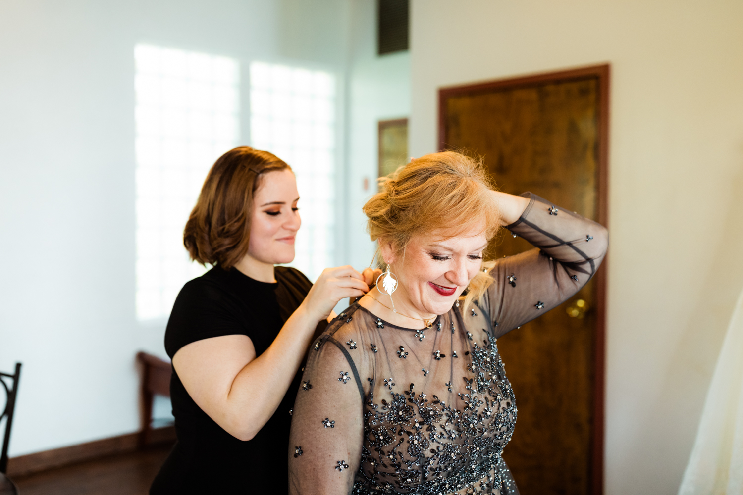 Mother of the bride putting on necklace on wedding day