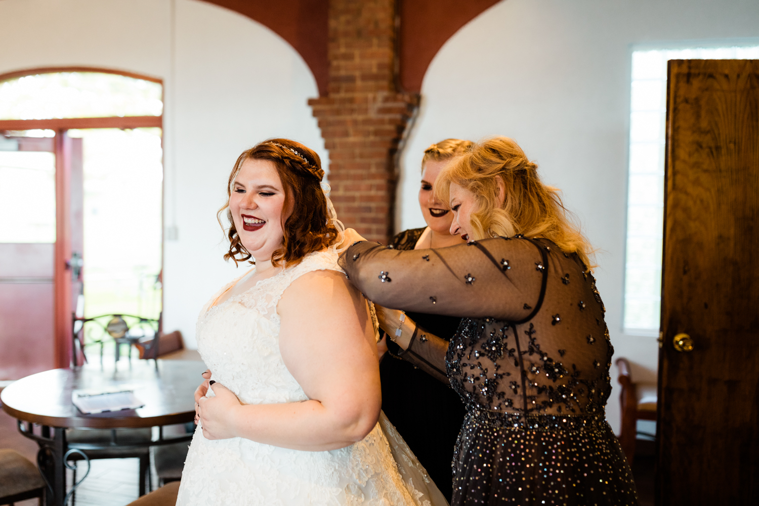 Laughing bride putting on wedding dress