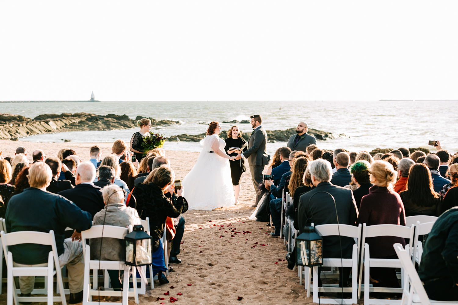 Guests watching bride and groom's ceremony on beach