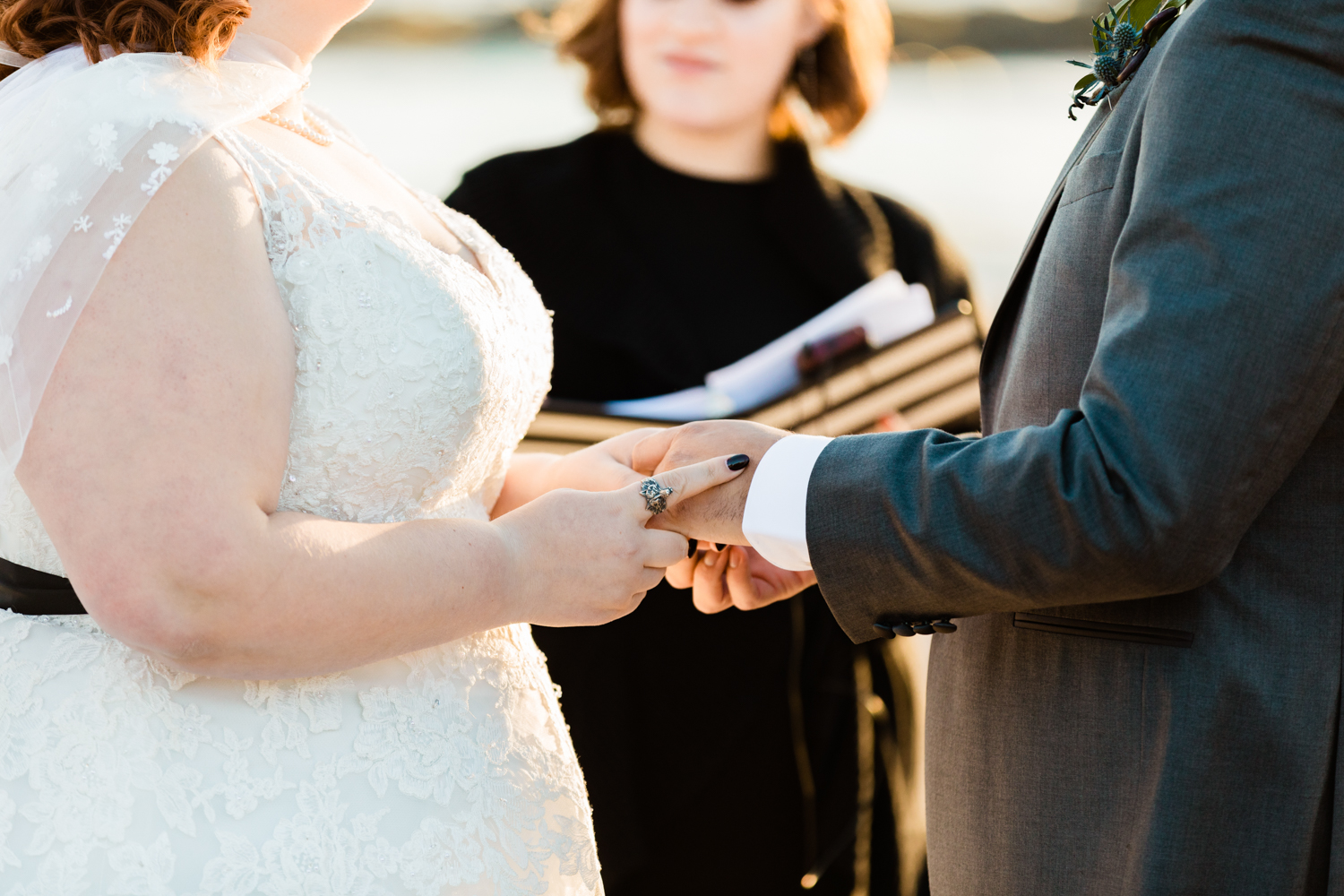 Bride wearing wolf ring exchanging wedding rings at beach ceremony