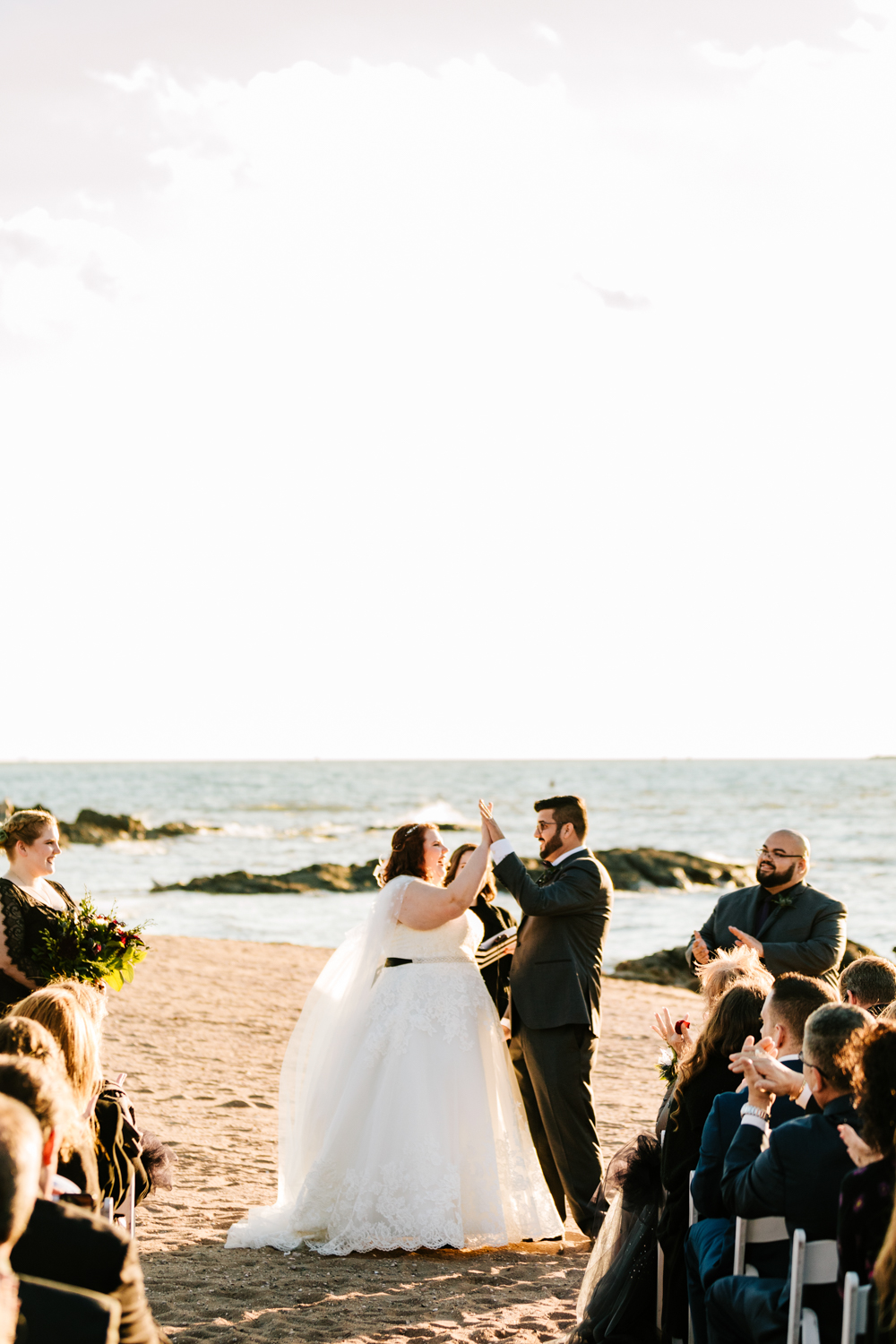 Bride and groom high five on beach ceremony