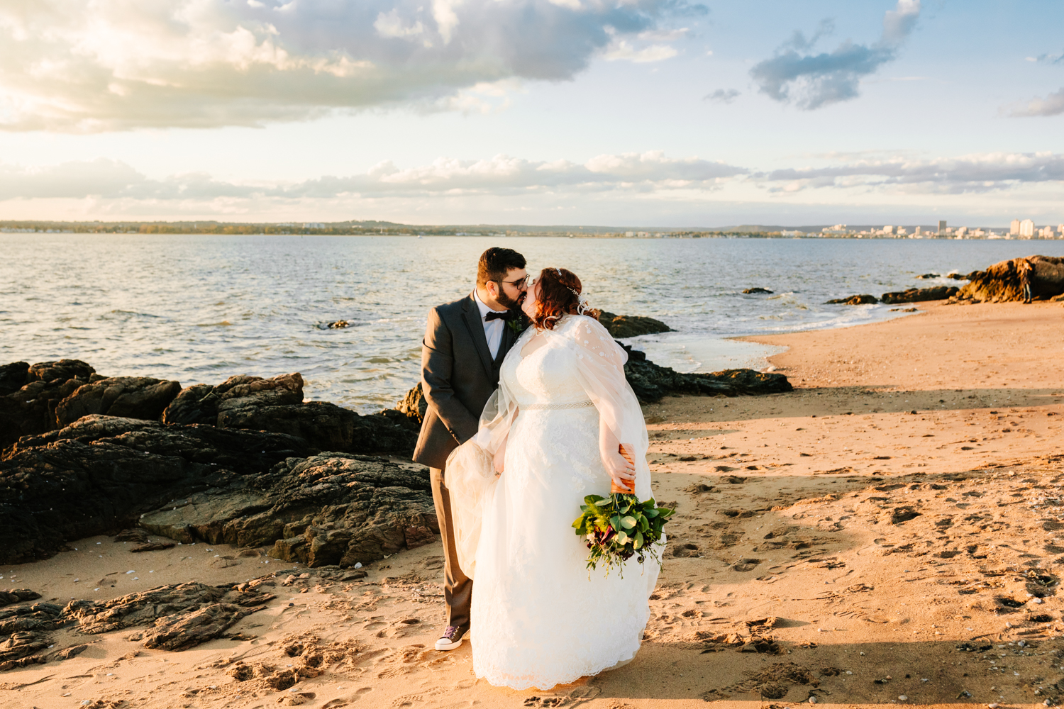 Bride and groom kiss on beach during sunset