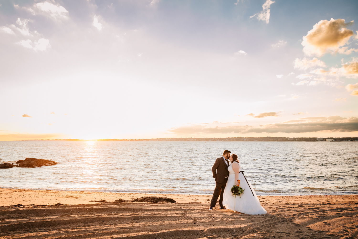 Landscape bride and groom at ocean at sunset