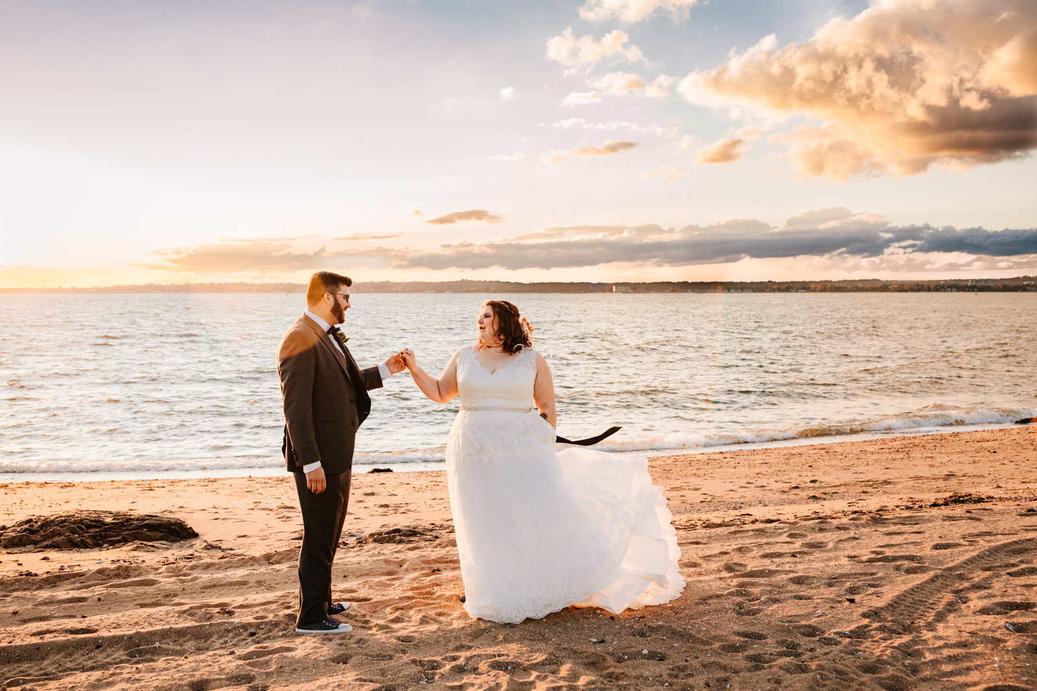 Bride and groom dancing on beach during sunset wedding day