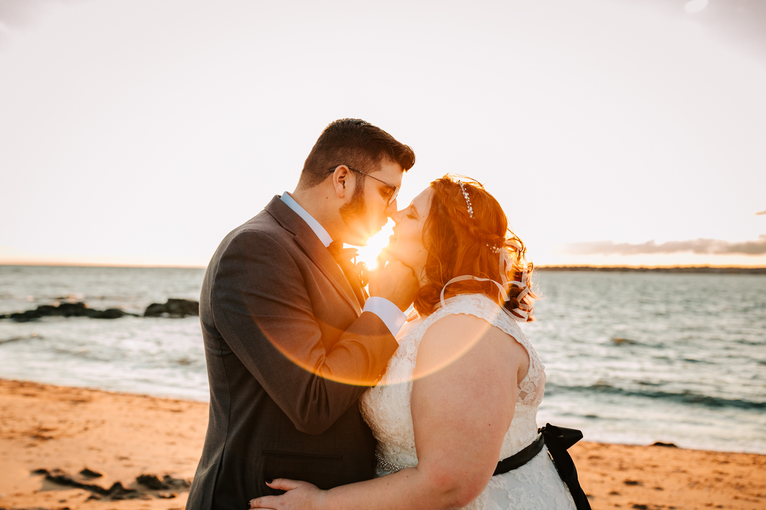 Sunflare with bride and groom kissing on sea wedding