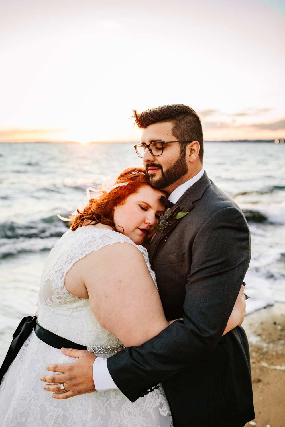 Black belt bride and groom hugging on beach at sunset